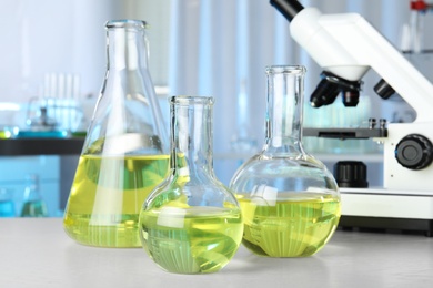 Photo of Different glassware with liquid on white table. Laboratory analysis