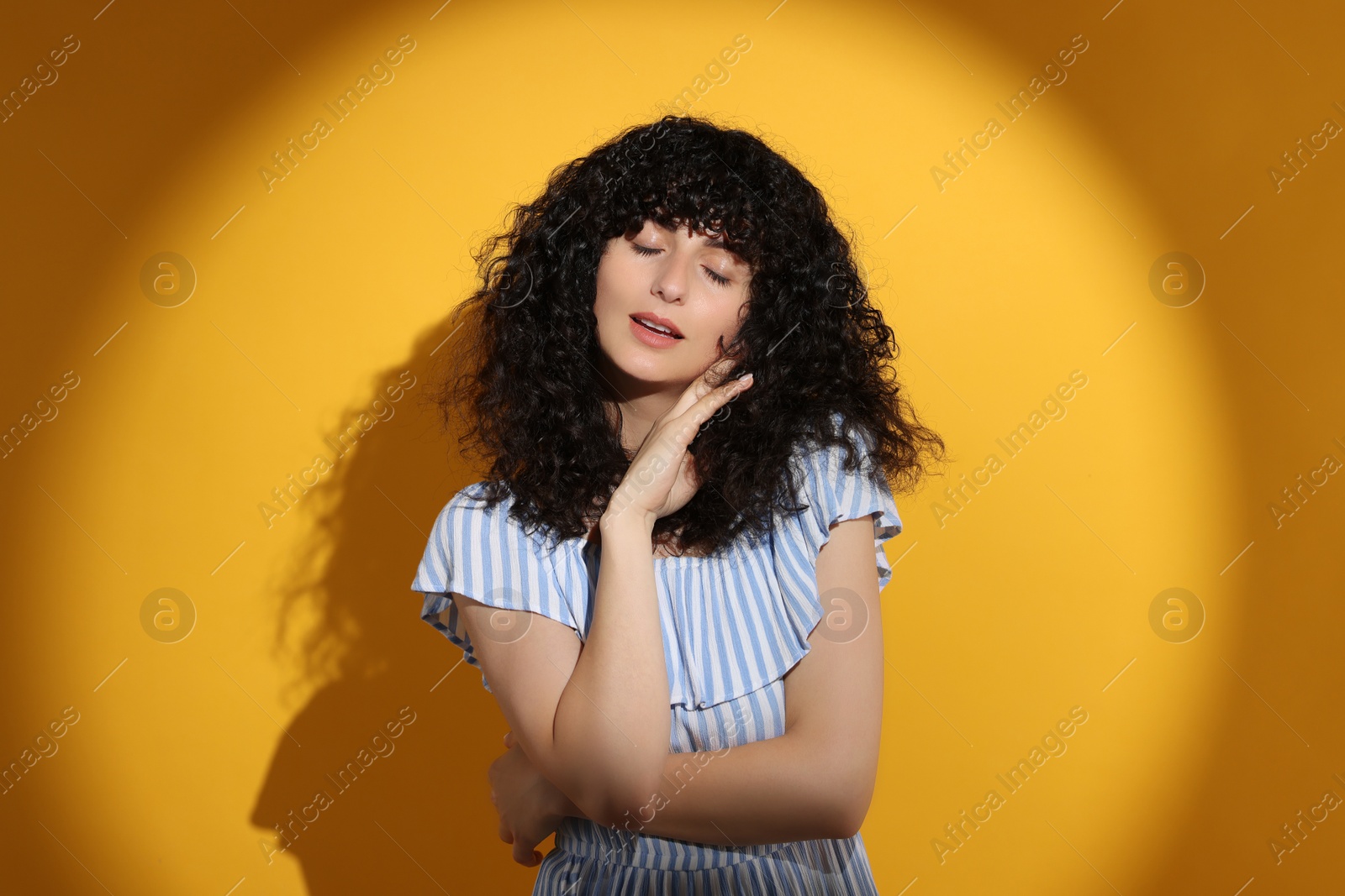 Photo of Beautiful young woman in sunlight on orange background