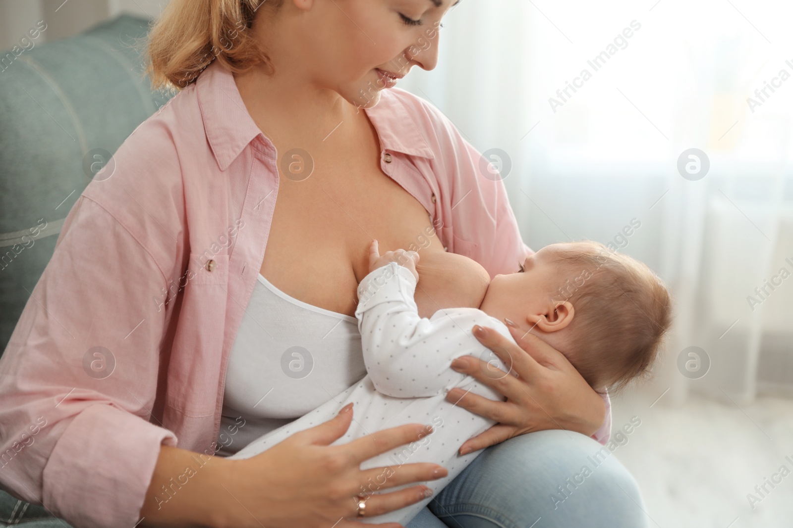 Photo of Young woman breastfeeding her baby at home