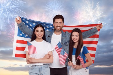 4th of July - Independence day of America. Happy family holding national flags of United States against sky with fireworks