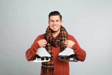 Photo of Happy man with ice skates on grey background