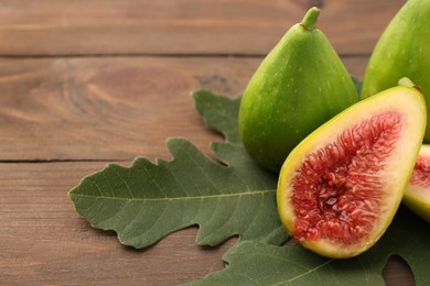 Photo of Cut and whole green figs on wooden table, closeup. Space for text