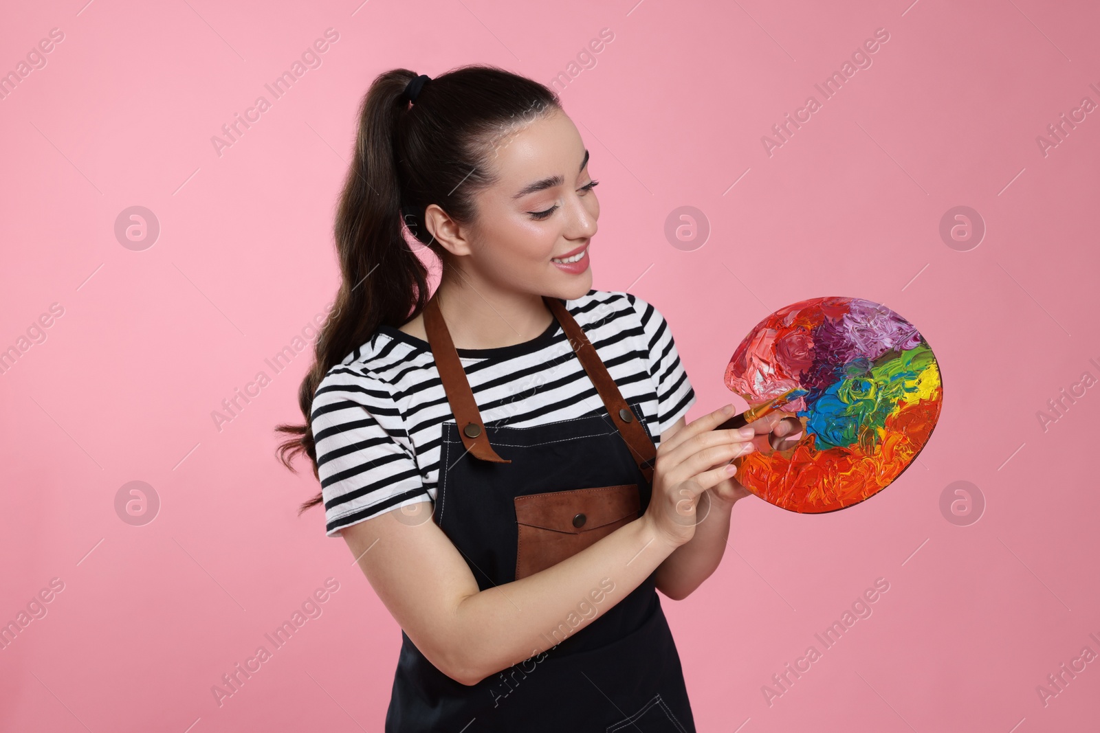 Photo of Woman with painting tools on pink background. Young artist