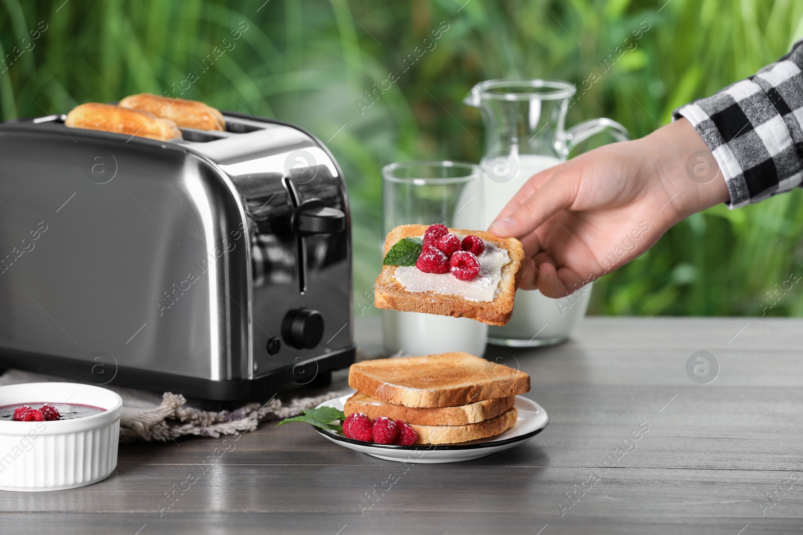 Photo of Woman taking tasty toasted sandwich at wooden table, closeup