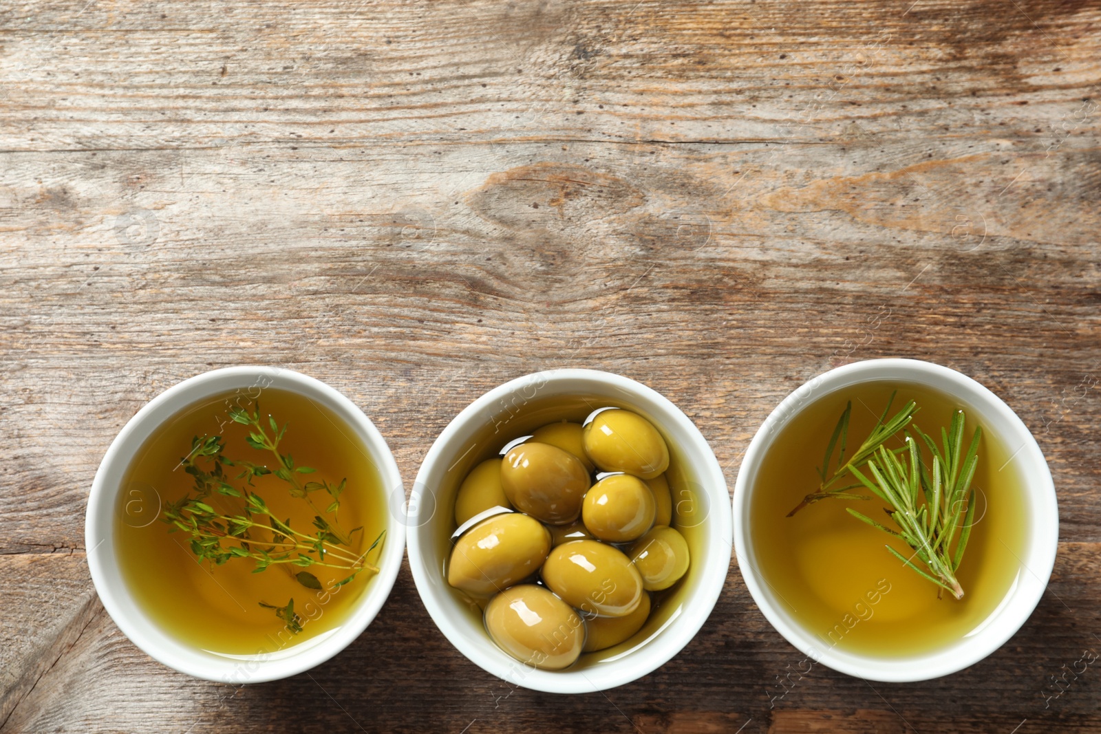 Photo of Beautiful composition with oil and ripe olives on wooden table, top view