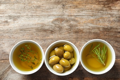 Photo of Beautiful composition with oil and ripe olives on wooden table, top view