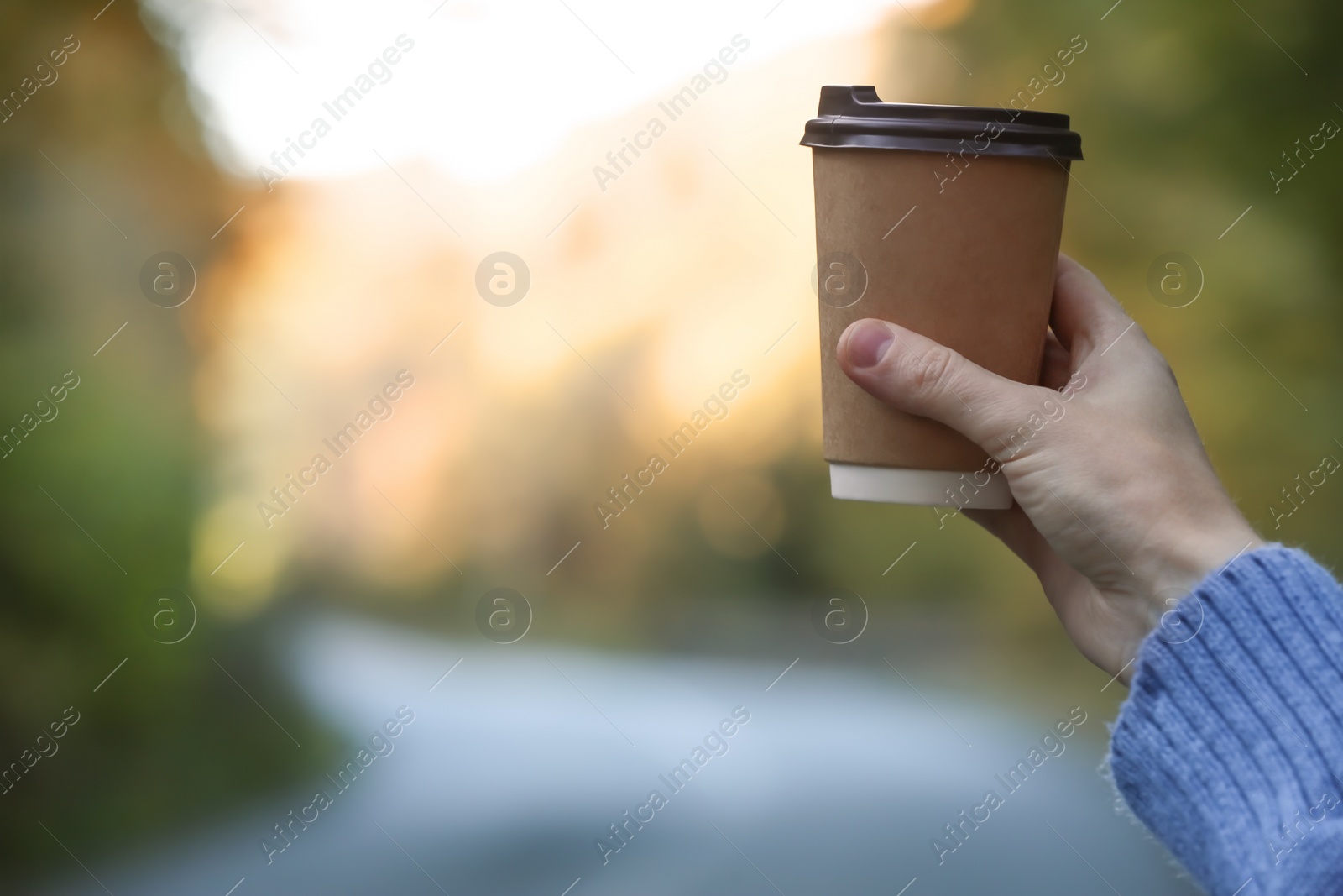 Photo of Woman holding takeaway coffee cup outdoors, closeup. Space for text
