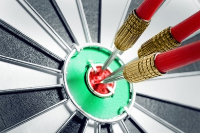 Dart board with red arrows hitting target, closeup