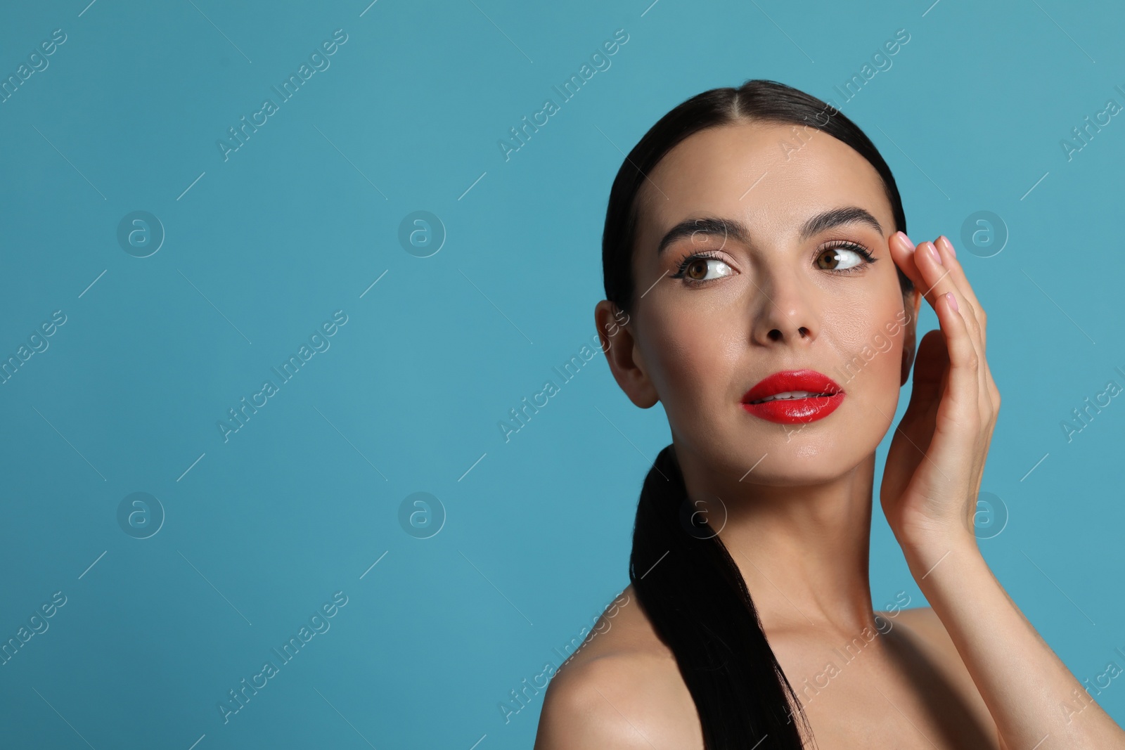 Photo of Attractive woman touching face against light blue background. Space for text