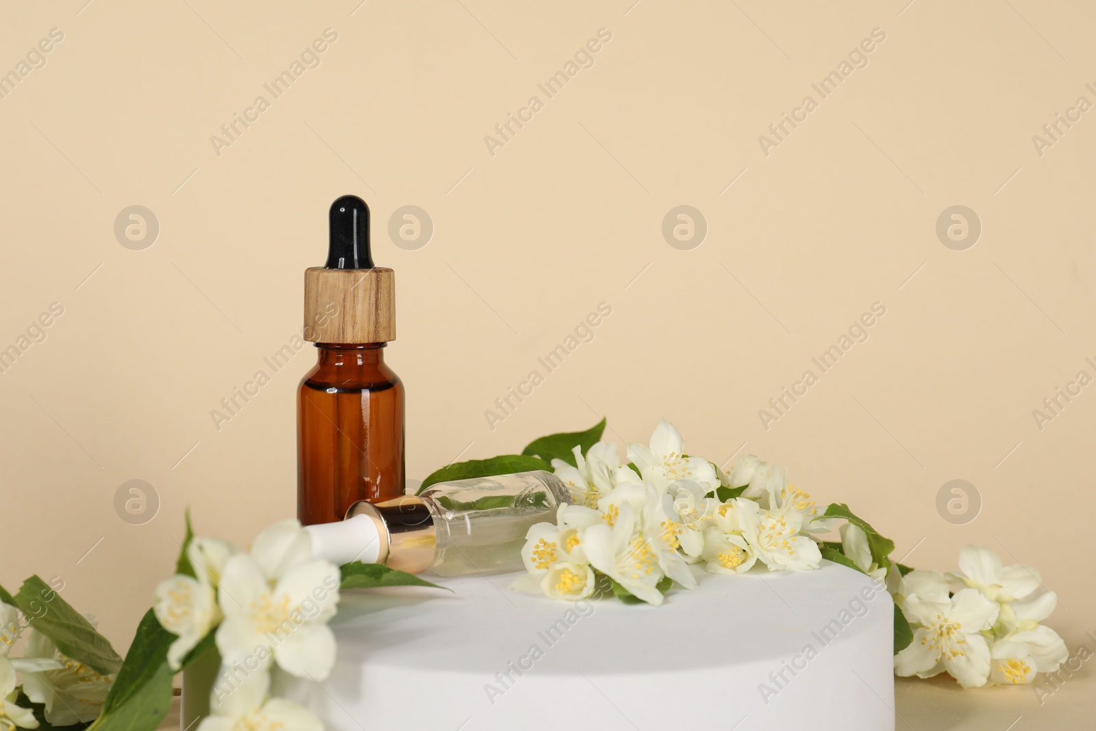 Photo of Presentation of essential oils in bottles and beautiful jasmine flowers against beige background