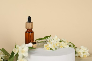 Presentation of essential oils in bottles and beautiful jasmine flowers against beige background