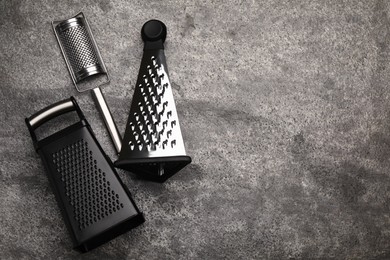 Different modern graters on grey table, flat lay. Space for text
