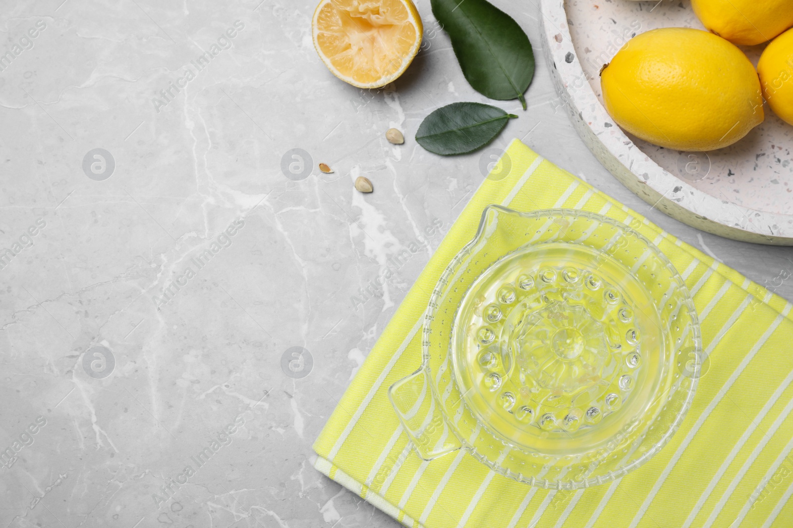 Photo of Flat lay composition with freshly squeezed lemon juice on grey table. Space for text