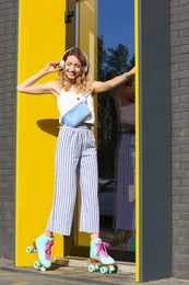 Photo of Happy girl with retro roller skates standing near glass door