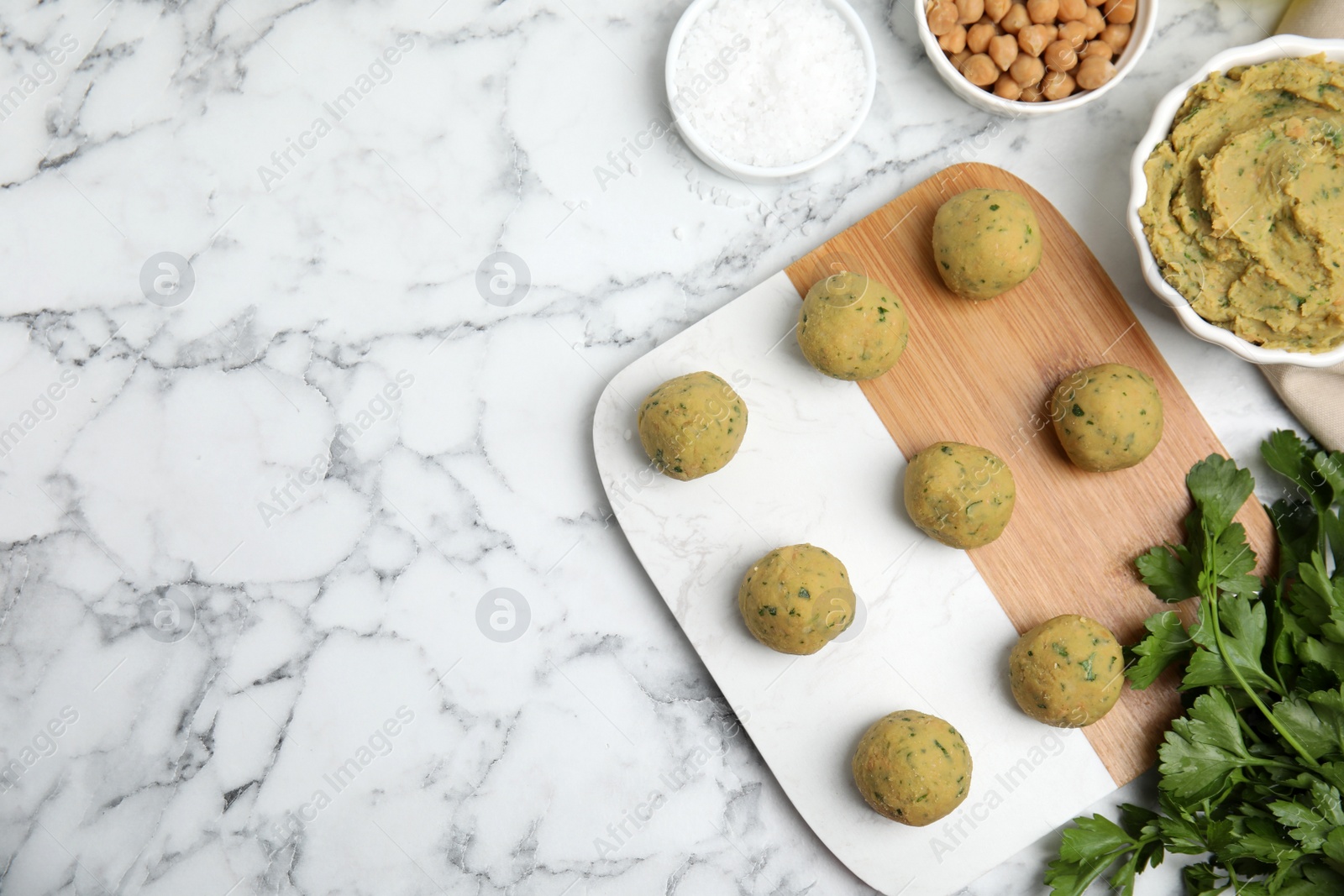 Photo of Raw falafel balls and ingredients on white marble table, flat lay. Space for text