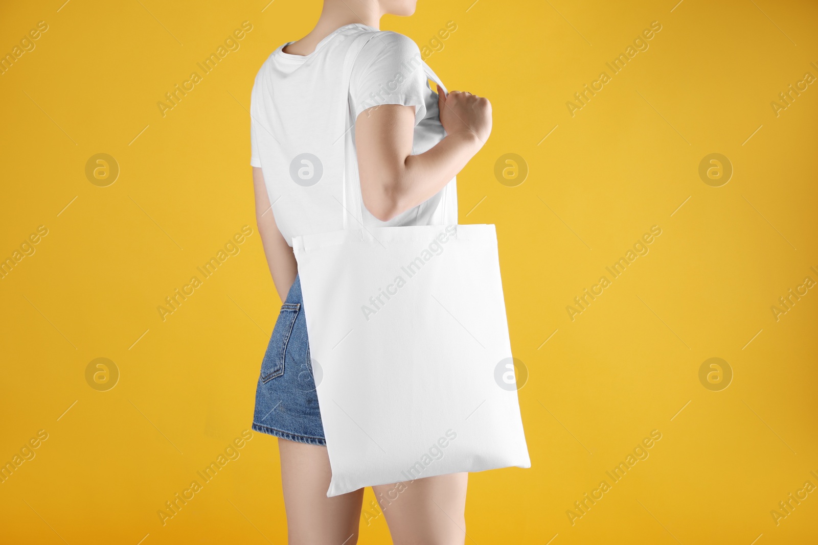 Photo of Woman with white textile bag on orange background, closeup. Space for design