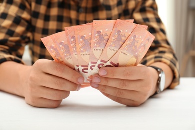 Photo of Man with Euro banknotes at table indoors, closeup