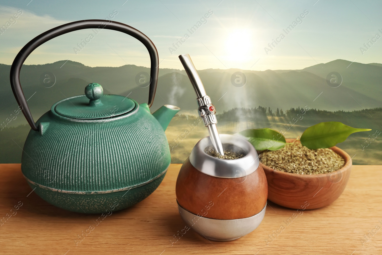 Image of Calabash with mate tea, bombilla and teapot on wooden table and beautiful view of mountain landscape