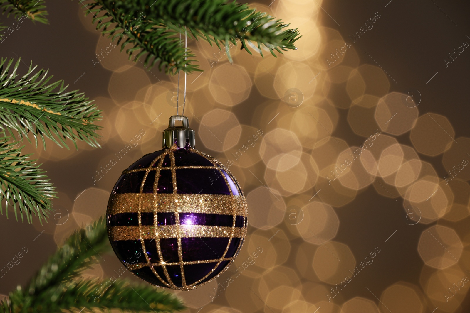 Photo of Beautiful bauble hanging on Christmas tree against blurred festive lights, closeup. Space for text