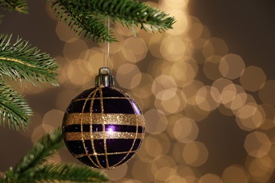 Photo of Beautiful bauble hanging on Christmas tree against blurred festive lights, closeup. Space for text