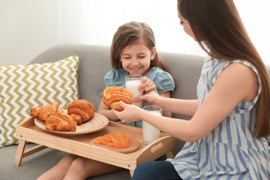 Mother and daughter having breakfast with milk in living room