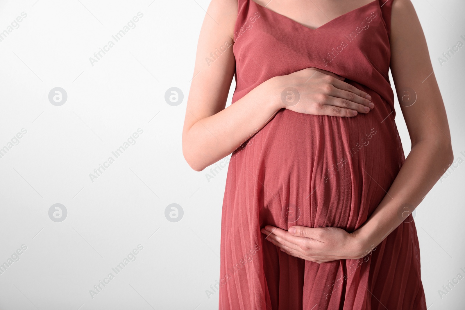 Photo of Young pregnant woman on light background, closeup. Space for text