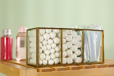 Organizer with many tampons on wooden table against light green background. Menstrual hygienic product