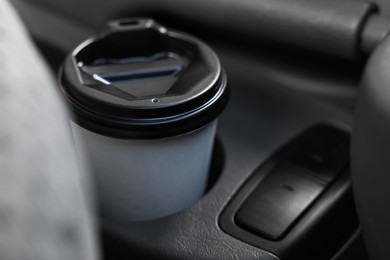 Coffee to go. Paper cup with tasty drink in holder inside of car, closeup