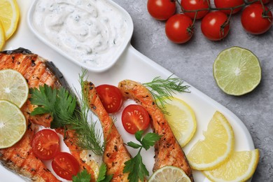 Photo of Tasty grilled salmon steaks and ingredients on light grey table, flat lay