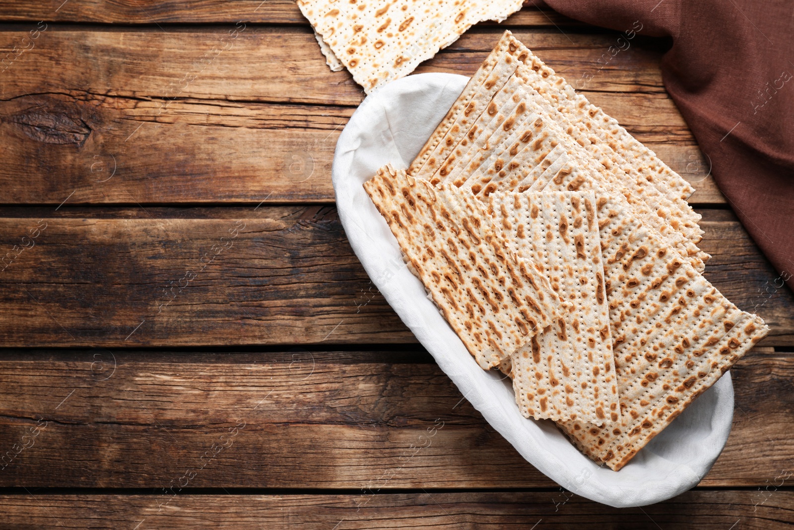 Photo of Traditional matzos in basket on wooden table, flat lay. Space for text