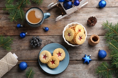 Photo of Traditional Linzer cookies with sweet jam and Christmas decorations on wooden background, top view
