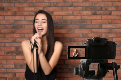 Image of Music teacher recording singing lesson near brick wall