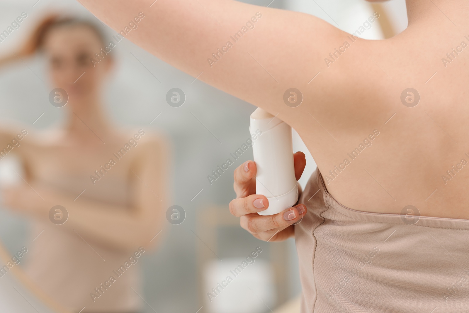 Photo of Beautiful woman applying deodorant near mirror in bathroom, selective focus