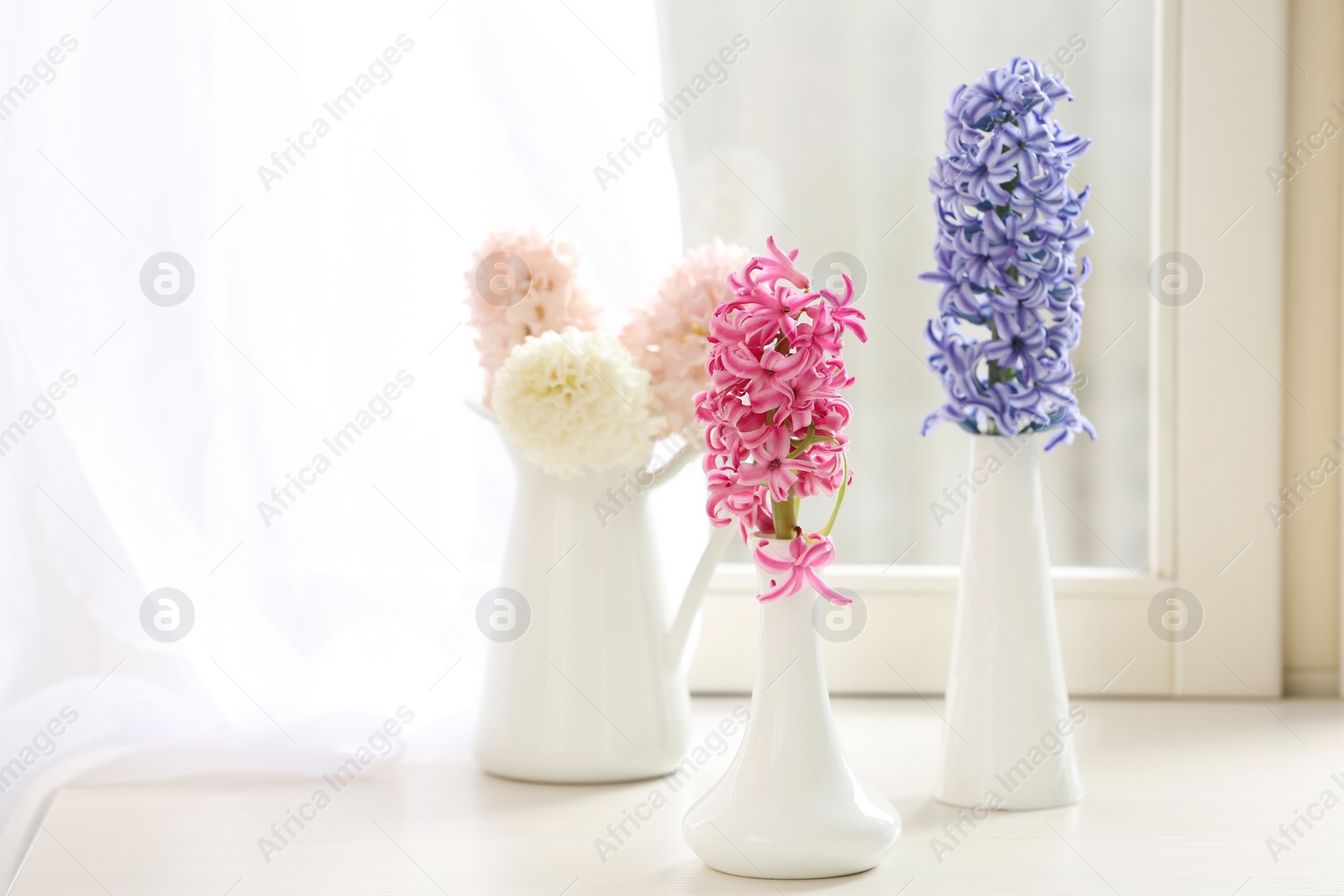 Photo of Beautiful fresh hyacinths on window sill indoors. Spring flowers