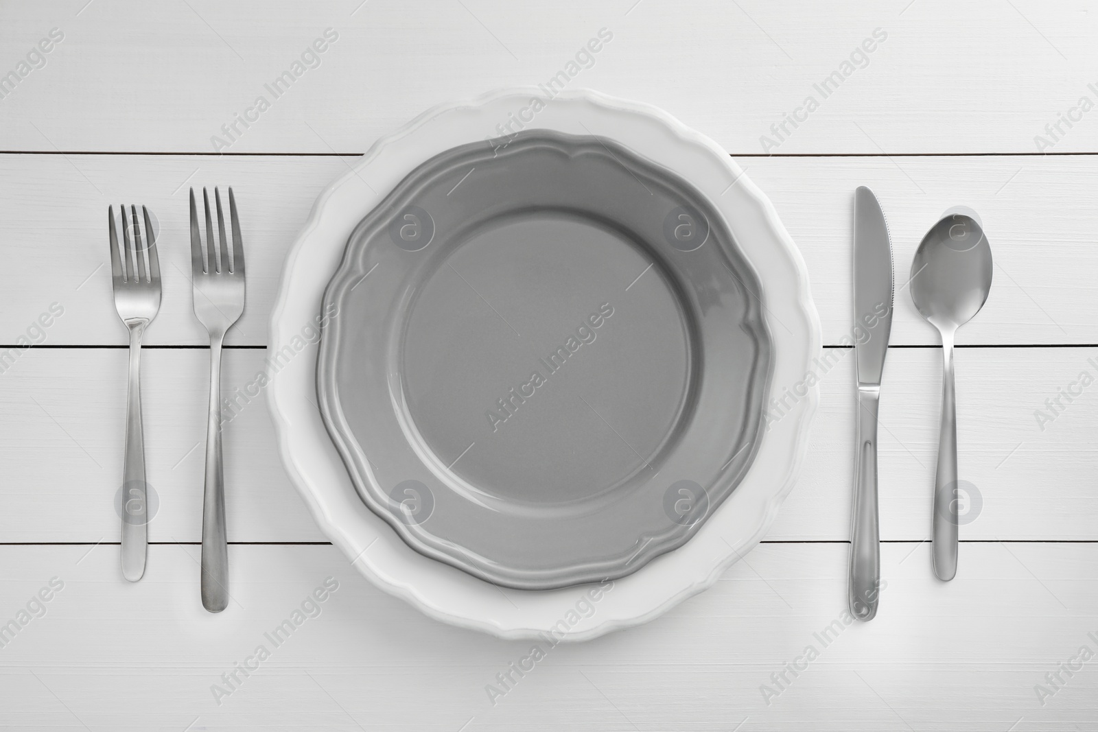 Photo of Stylish setting with cutlery and plates on white wooden table, flat lay