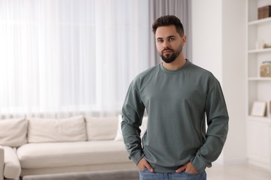 Photo of Handsome man in stylish sweater at home, space for text