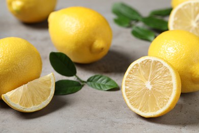 Fresh lemons and green leaves on grey table, closeup