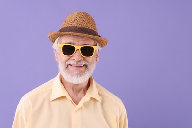 Photo of Portrait of stylish grandpa with sunglasses and hat on purple background, space for text