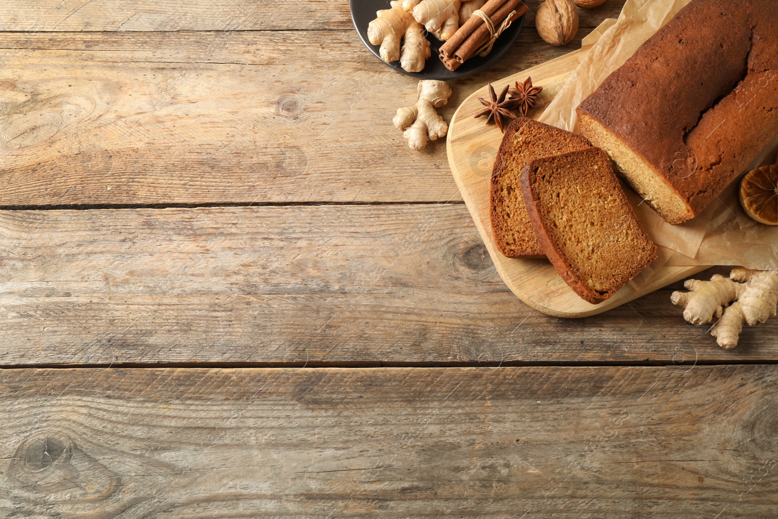 Photo of Delicious gingerbread cake and ingredients on wooden table, flat lay. Space for text