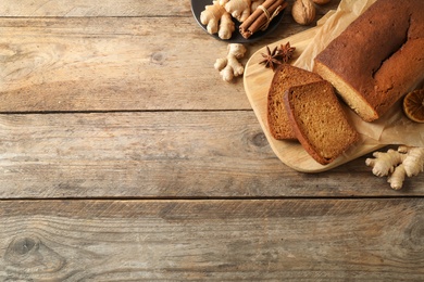 Photo of Delicious gingerbread cake and ingredients on wooden table, flat lay. Space for text