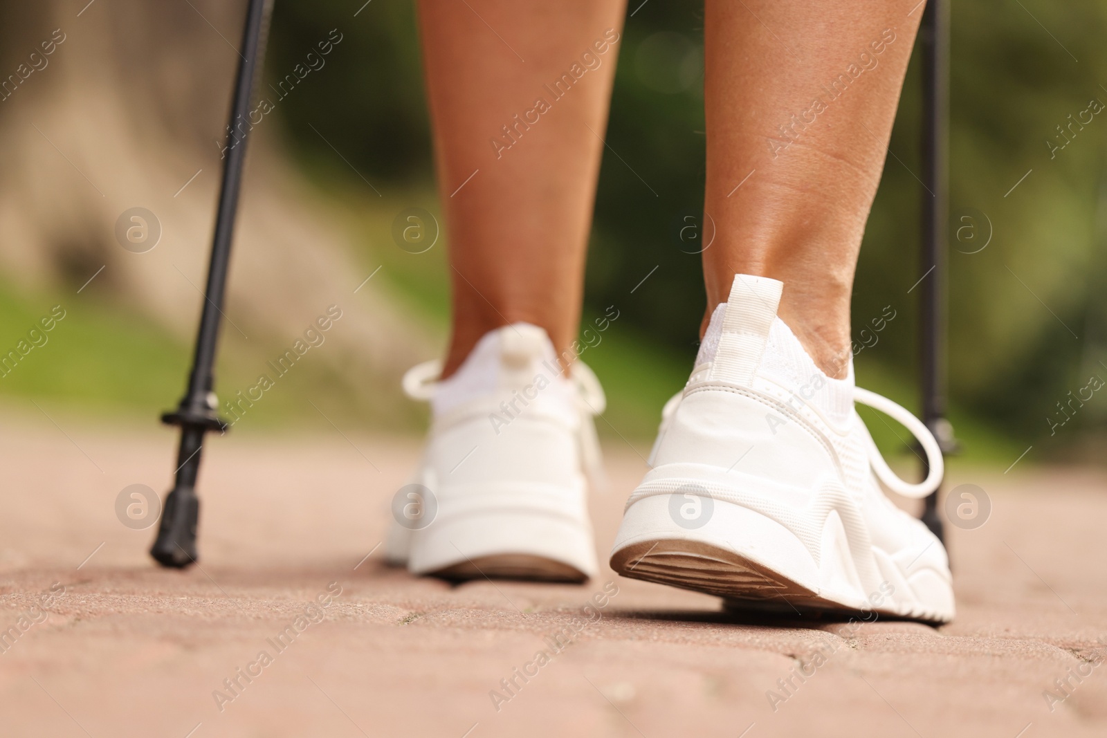 Photo of Woman performing Nordic walking outdoors, closeup view