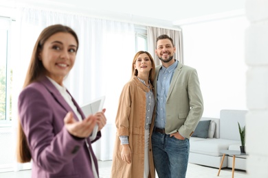 Photo of Female real estate agent showing new house to couple, indoors