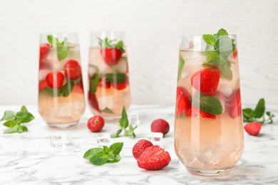 Photo of Glasses of refreshing drink with strawberry and mint on marble table, space for text