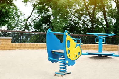 Photo of Children's playground with bright butterfly shaped spring rider and roundabout