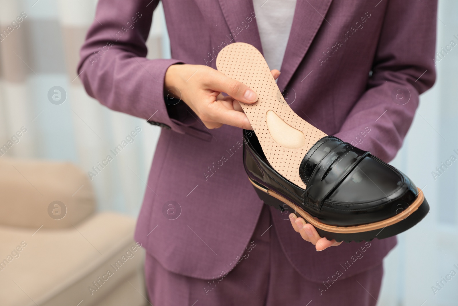 Photo of Woman putting orthopedic insole into shoe indoors, closeup. Foot care