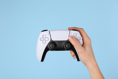 Photo of Woman with game controller on light blue background, closeup