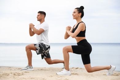 Couple doing exercise together on beach. Body training