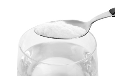 Photo of Spoon with baking soda over glass of water on white background