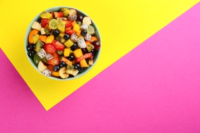 Photo of Delicious exotic fruit salad on color background, top view. Space for text