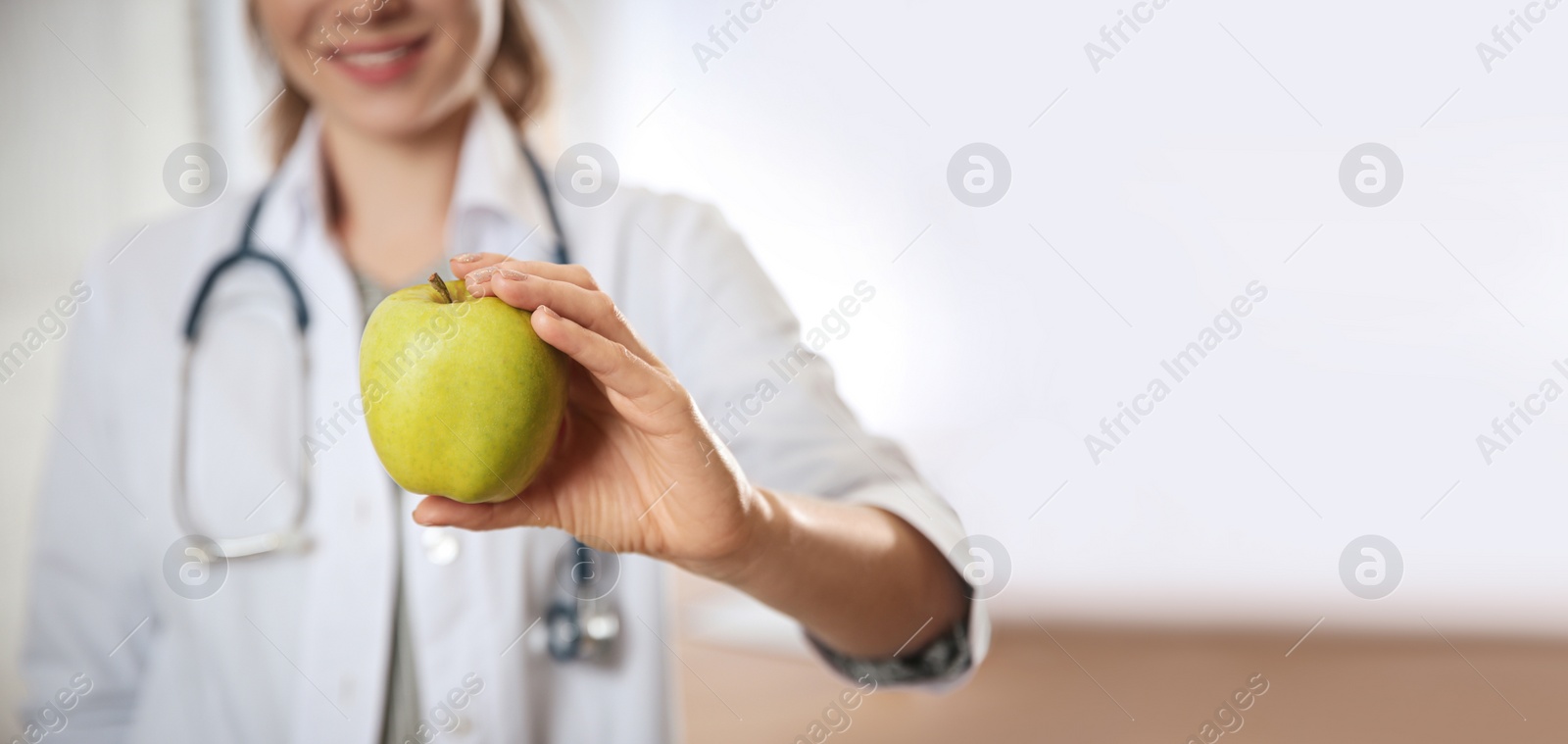 Image of Nutritionist with fresh apple in her office, closeup view with space for text. Banner design